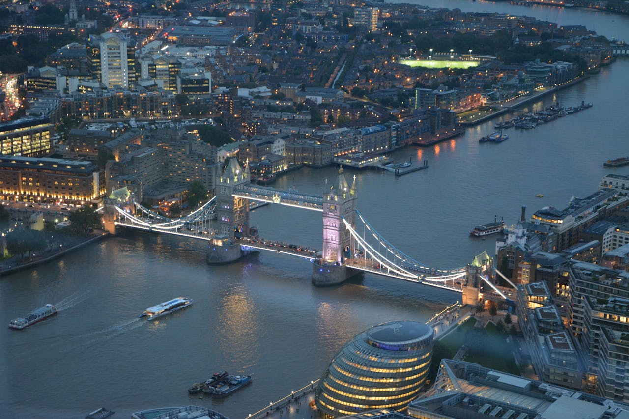 A stunning aerial photograph capturing London's Tower Bridge illuminated at night over the Thames River.